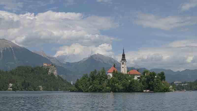 Lake Bled island church & castle, Julian Alps – Slovenia Escape 2026 Lake Bled, Slovenia – island with the Church of the Assumption, Bled Castle on its cliff, and the Julian Alps reflected in the lake