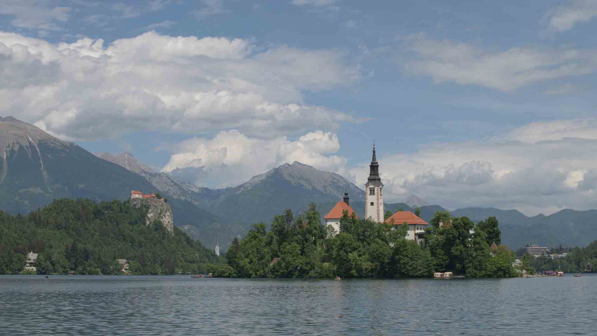 Lake Bled island church & castle, Julian Alps – Slovenia Escape 2026 Lake Bled, Slovenia – island with the Church of the Assumption, Bled Castle on its cliff, and the Julian Alps reflected in the lake