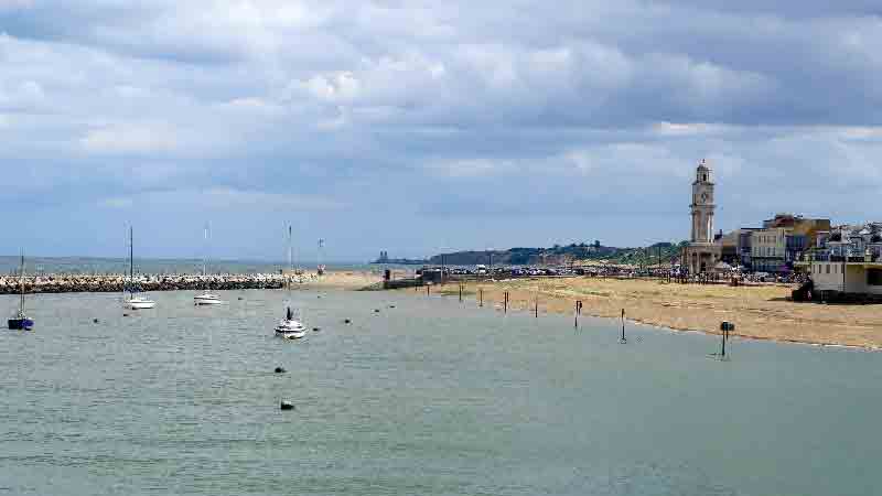Herne Bay seafront and Clock Tower in Kent, England. Herne Bay seafront with Clock Tower, sandy beach, and sailboats, Kent, UK.