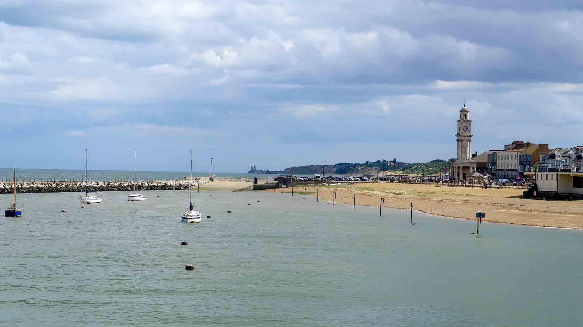 Herne Bay seafront and Clock Tower in Kent, England. Herne Bay seafront with Clock Tower, sandy beach, and sailboats, Kent, UK.
