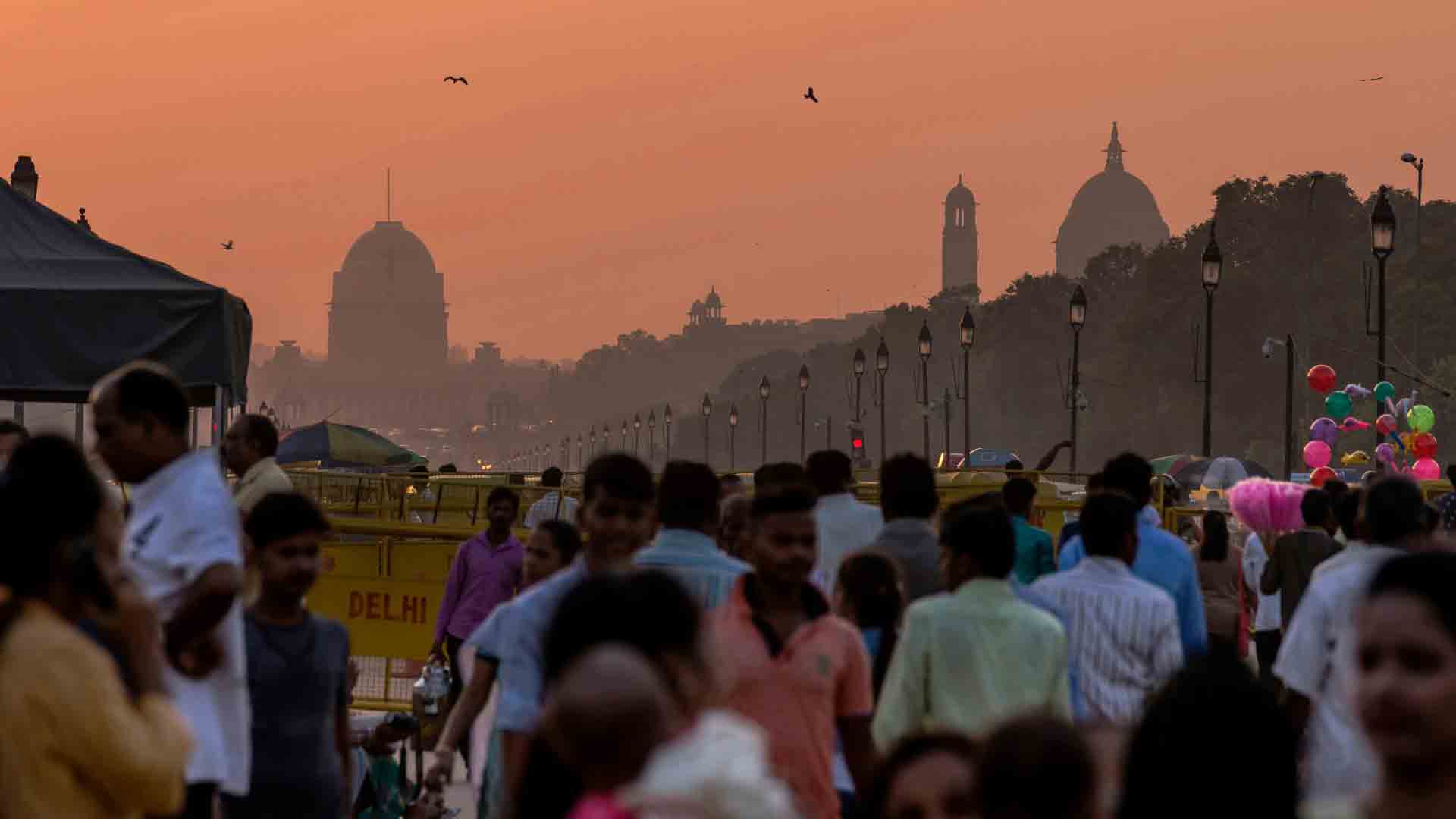Sunset over New Delhi - A Bustling Evening at India Gate Crowded street in New Delhi at sunset with silhouettes of iconic buildings and lively street life.